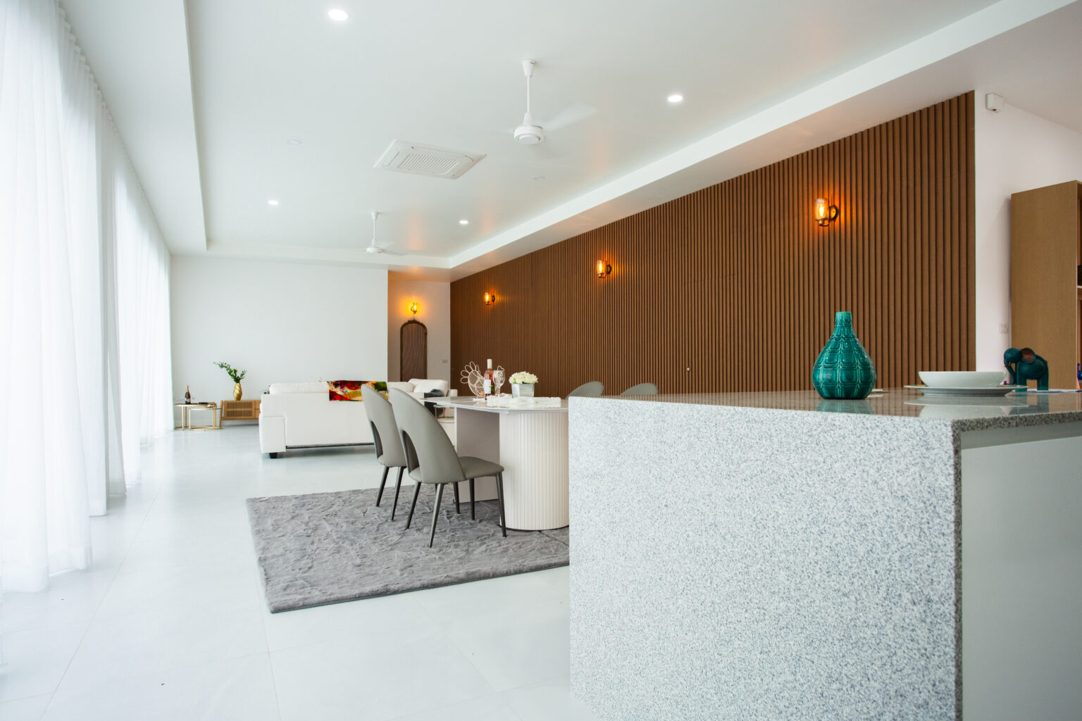 Close-up of a striped cat resting beside a wooden scratching post with soft blurred foreground elements.