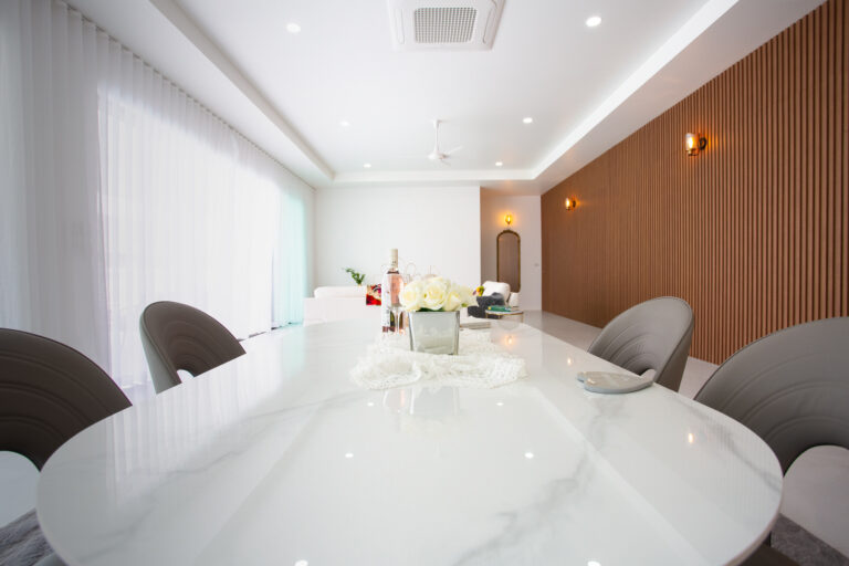 Bright modern meeting room with white oval table, gray chairs, and wooden wall panel